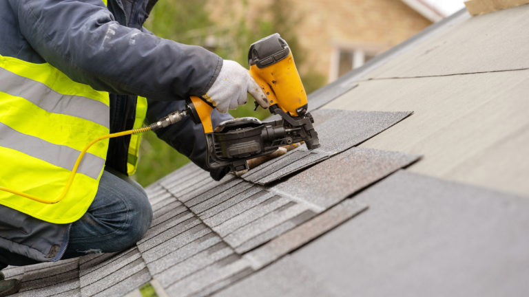Closeup of asphalt shingles being installed on a roof
